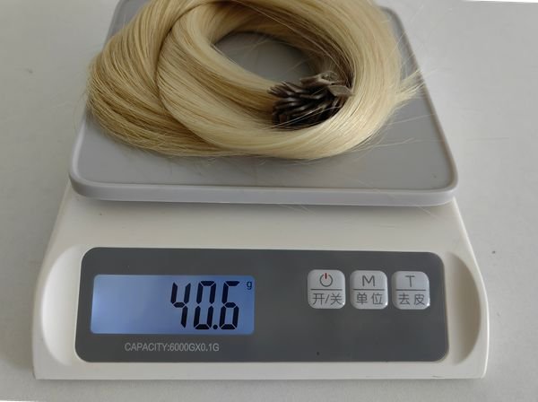 A person using a measuring tape and scale to check the length and weight of human hair extensions